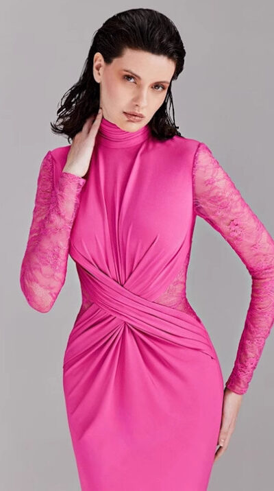 Model wearing a stylish pink dress with long lace sleeves and a fitted silhouette, showcasing a modern and elegant design. The dress features a high neckline and intricate draping details, perfect for formal occasions.