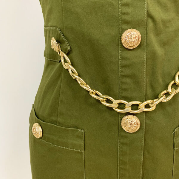 Close-up of a green garment featuring gold lion-embossed buttons and a stylish gold chain belt, highlighting a modern and chic design.