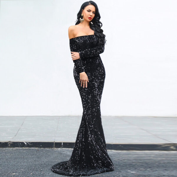 Elegant woman wearing a stunning off-the-shoulder black sequined gown, posing gracefully on a city street. The dress features a fitted silhouette that flares at the bottom, accentuating her figure, while her long, wavy hair and bold red lipstick complete the glamorous look.