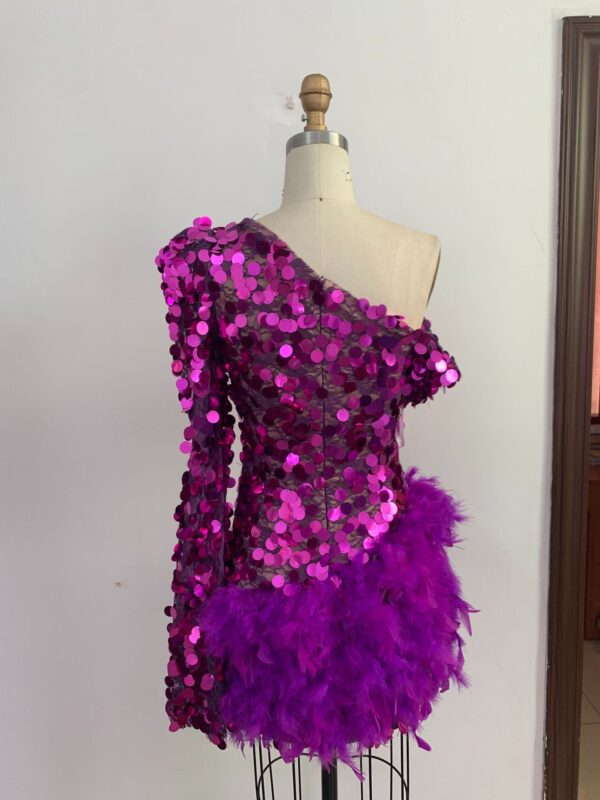 One-shoulder purple sequin dress adorned with feathers, showcased on a dress form against a plain background, perfect for evening wear or special occasions.