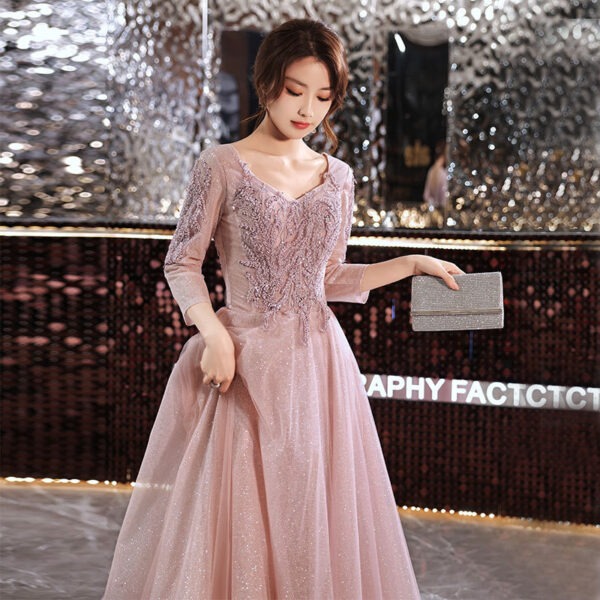 Elegant woman in a sparkling pink evening gown with intricate embroidery, holding a silver clutch, set against a glamorous backdrop with mirrored accents. Perfect for formal occasions and special events.