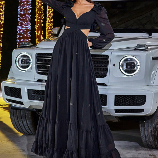 Woman posing in a long black dress in front of a white luxury SUV.