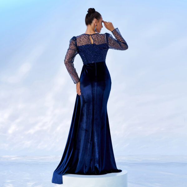 Elegant woman wearing a navy blue evening gown with sheer, beaded long sleeves and a fitted silhouette, showcasing a sophisticated back view against a soft, light background.