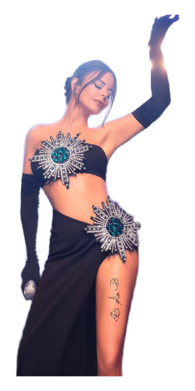 Model in a stylish black gown featuring intricate beaded embellishments, posing elegantly with one arm raised. The dress showcases a high slit and is complemented by long black gloves, while subtle tattoos are visible on her thigh.