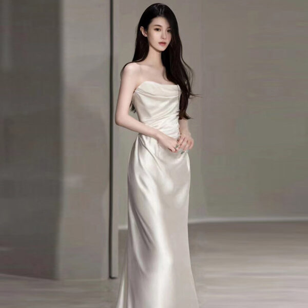 Elegant woman in a satin strapless wedding dress, showcasing a fitted bodice and flowing skirt, set against a minimalist background. Perfect for bridal fashion inspiration.