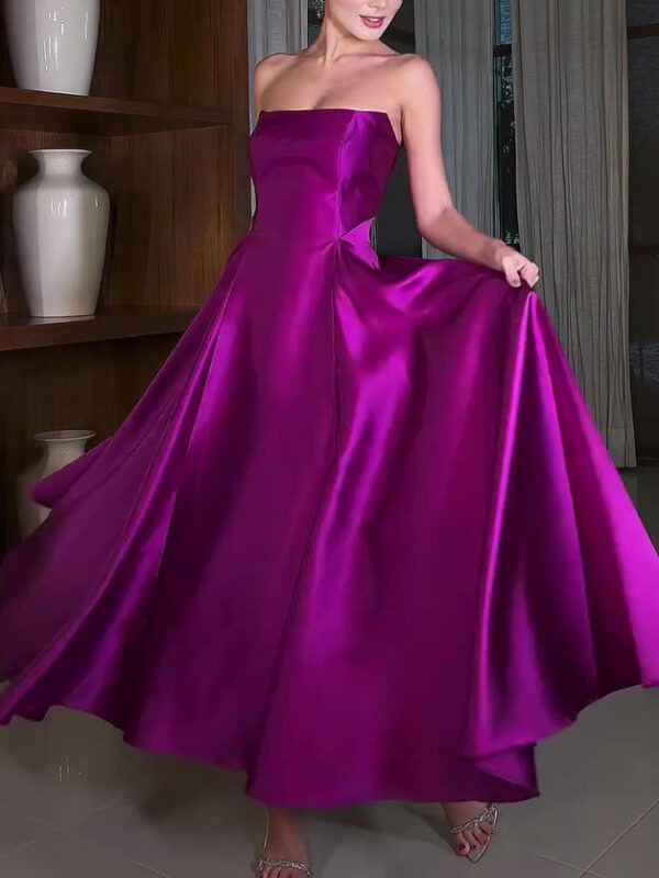 A woman twirls in a stunning strapless purple evening gown, showcasing its flowing skirt and elegant silhouette against a modern interior backdrop.