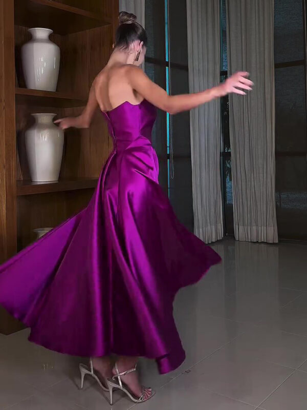 Woman in a vibrant purple satin gown twirling gracefully in a modern indoor setting, showcasing the dress's flowing silhouette and elegant design.