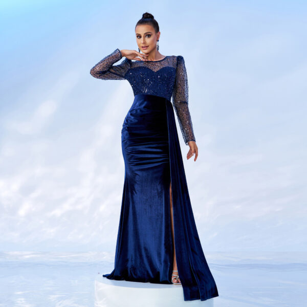 Elegant woman in a sparkling navy blue evening gown with long sequined sleeves and a thigh-high slit, posing against a soft blue background. The dress features a sweetheart neckline and a fitted silhouette, perfect for formal occasions.