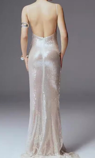 Elegant back view of a woman wearing a shimmering, floor-length gown with a low back and thin straps, showcasing a sophisticated design perfect for formal occasions.