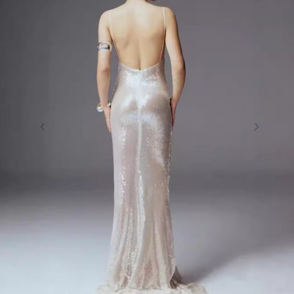 Elegant back view of a woman wearing a shimmering, floor-length gown with a low back and thin straps, showcasing a sophisticated design perfect for formal occasions.