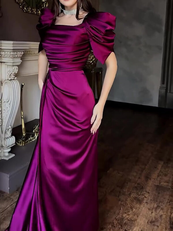 Elegant woman wearing a stunning purple satin evening gown with puffed sleeves and a fitted silhouette, posing in a luxurious indoor setting.