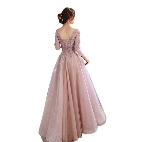 Elegant back view of a woman wearing a stunning long-sleeve evening gown in soft pink, featuring intricate beadwork and a flowing tulle skirt, perfect for formal events and special occasions.