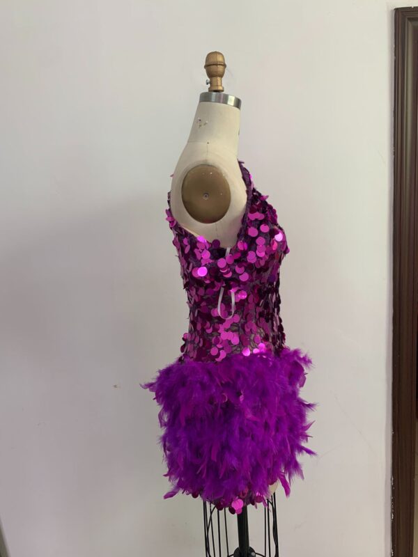 Vibrant pink sequin dress with feathered hem displayed on a dress form, showcasing a glamorous and playful design suitable for parties or performances.