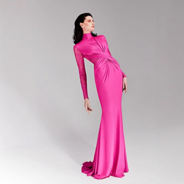 Model wearing a vibrant pink evening gown with a high neckline and one long lace sleeve, showcasing elegant draping and a fitted silhouette against a neutral background.