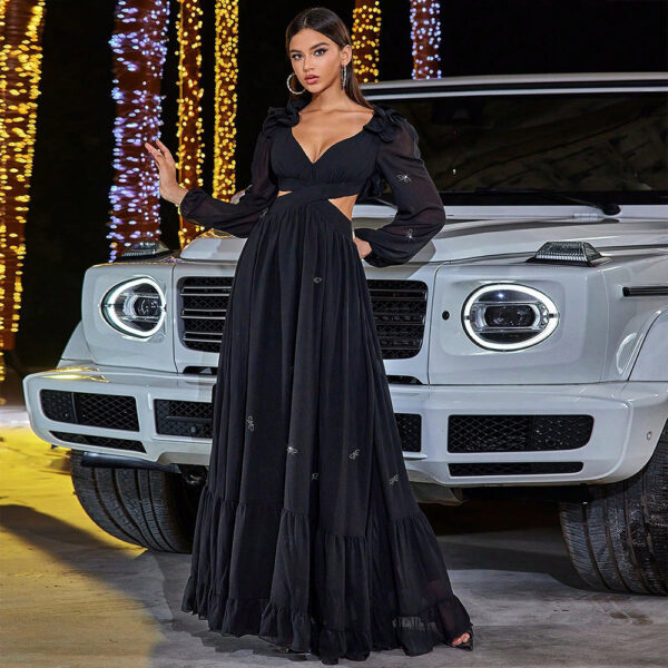 Stylish woman in a black cut-out maxi dress with puff sleeves poses beside a luxury white SUV against a backdrop of twinkling lights. The elegant outfit features intricate embroidery, highlighting a chic evening look.