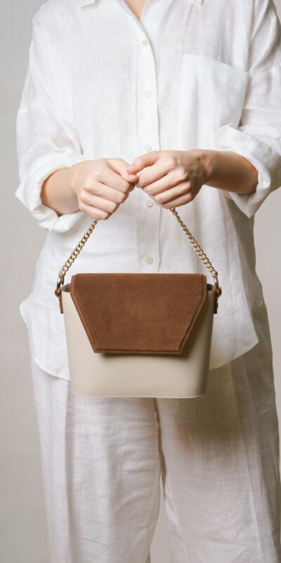 Woman in white outfit holding a chic handbag, minimalist fashion style.