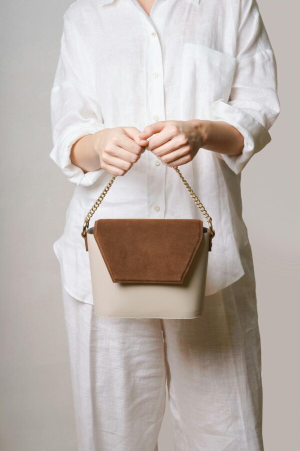 Woman in white outfit holding a chic handbag, minimalist fashion style.