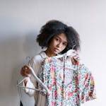 Young woman selecting floral dresses in a cozy home, embracing morning routine.