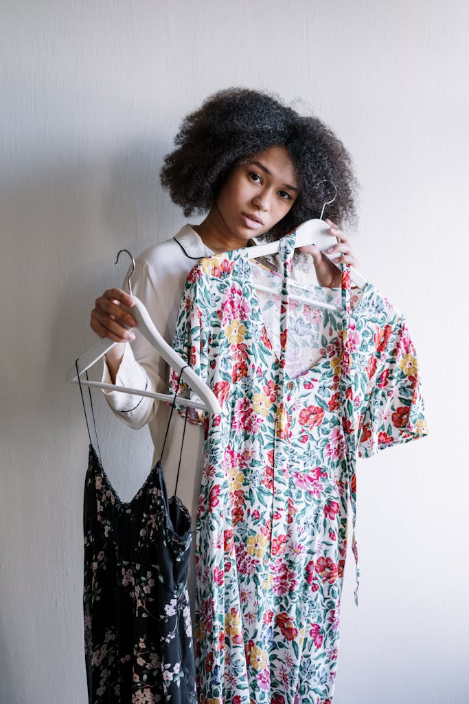 Young woman selecting floral dresses in a cozy home, embracing morning routine.